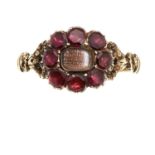 AN ANTIQUE HAIRWORK AND GARNET MOURNING RING in high carat yellow gold, set with a central panel