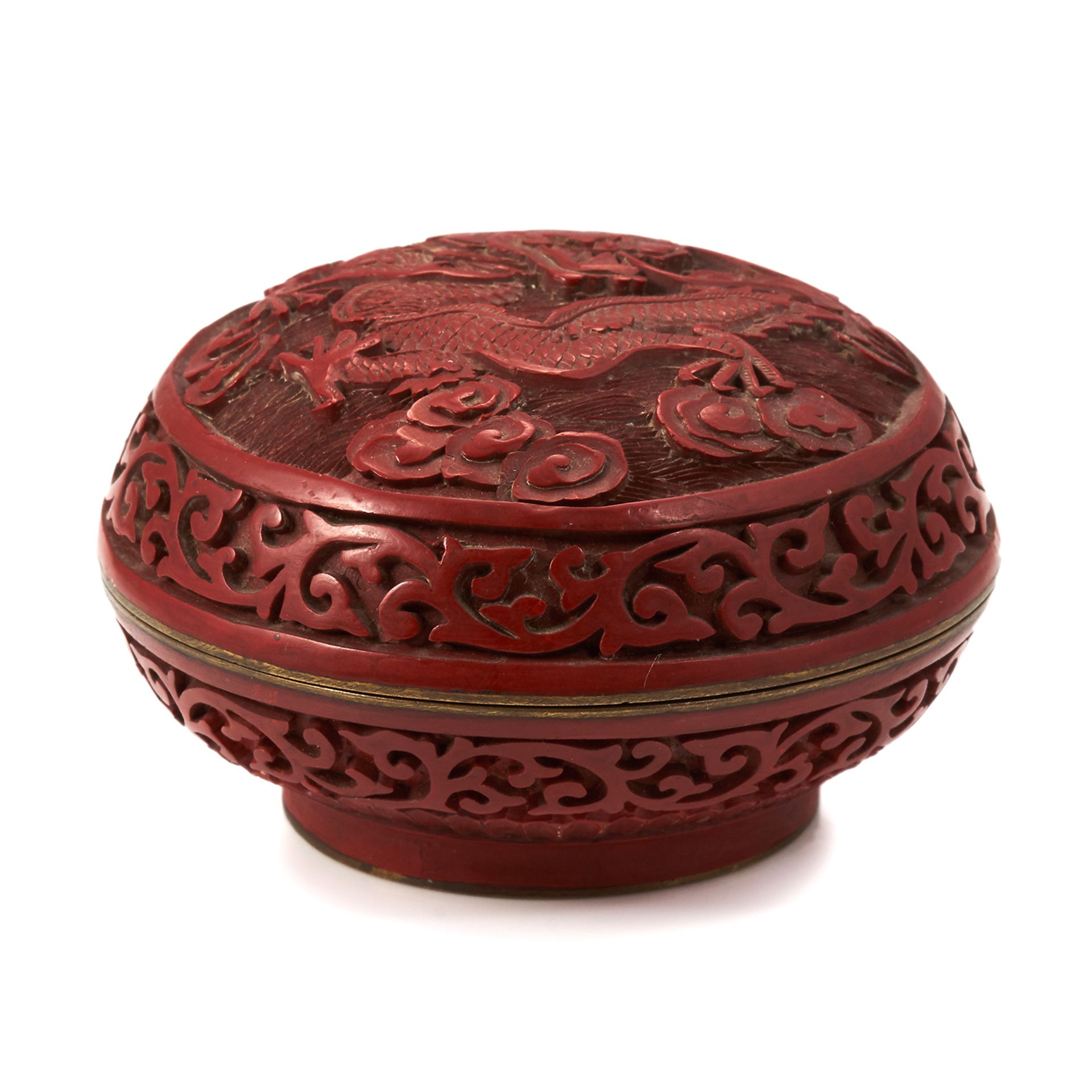 A CARVED CINNABAR AND BRONZE BOX of circular form, the bronze body with enamelled interior,