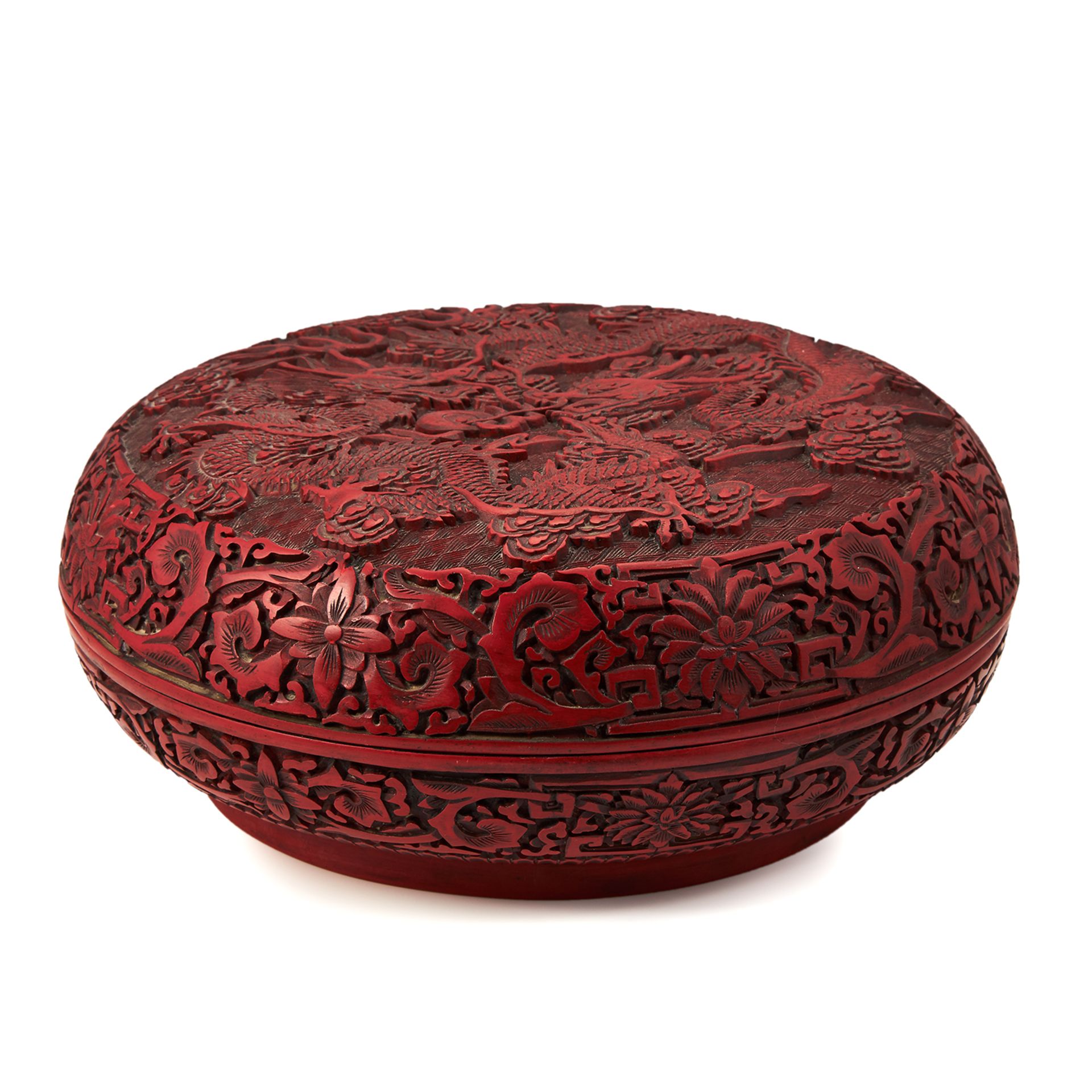 A LARGE CHINESE CARVED CINNABAR BOX of circular form, the lid with detailed carvings of dragons