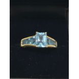 9ct gold ring set with princess cut blue topaz graduating to shoulders (sz T)