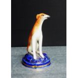 A Staffordshire pottery Hound, modelled seated on a blue circular base, 10cm high