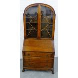 An Art Deco oak bureau bookcase, the arched top over a pair of astragal glazed doors with a