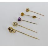 A collection of five tiepins to include a 15 carat gold and diamond set example and a 9 carat gold