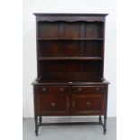 An oak dresser, with shelved back over two long drawers and a pair of panelled cupboard doors, on