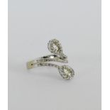 A white metal dress ring, stamped '750' of cross over design, set with baguette diamonds and