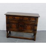 An oak cabinet, the rectangular top over two long drawers and a pair of carved cupboard doors, on