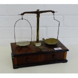 A set of brass balance scales on a mahogany base with two drawers