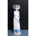 A NAO porcelain figure of a girl with long dress and sun hat, 32cm high