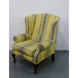 An upholstered wing back armchair on cabriole supports,