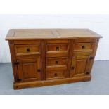 A hardwood sideboard, with an arrangement of five drawers and pair of cupboard doors, 132 x 84cm