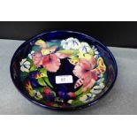A Moorcroft bowl tube line decorated with Orchids to a cobalt ground, 23cm diameter, impressed and