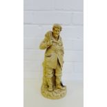 A cream glazed pottery figure of a Fisherman, modelled standing with a fishing basket at his side on