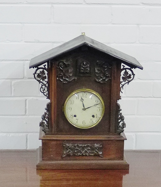 An oak mantle clock, the circular dial with Arabic numerals and flanked by carved leaf decoration 46