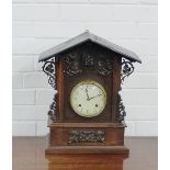 An oak mantle clock, the circular dial with Arabic numerals and flanked by carved leaf decoration 46