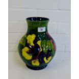 A Moorcroft green glazed baluster vase, tube line decorated with flower, it has a chip to the