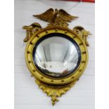 A Regency style convex wall mirror with ebonised slip and gilt ball and eagle surmount