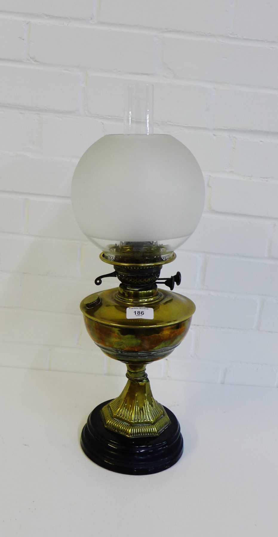 A brass oil lamp on circular hardstone base