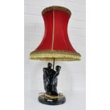 A matt black glazed figural table lamp base complete with a red velvet shade