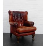 A brown leather armchair on claw and ball feet