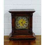 An oak mantle clock, the brass dial with silvered chapter ring and Roman numerals flanked by