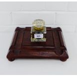 A square cut glass inkwell on a wooden base with four bun feet