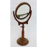 A mahogany framed oval mirror on a baluster column and circular base, 70cm high