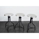 A set of three adjustable industrial style stools with circular brushed steel seats and black tripod