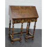 A walnut bureau with slope front, opening to reveal a fitted interior above three short drawers,