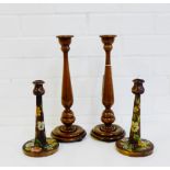 A pair of fruit wood candlesticks and another pair of floral painted wooden candlesticks, tallest