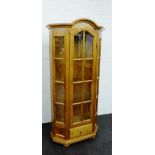 A pine display cabinet with an arch pediment top with glazed panelled doors over a single drawers on