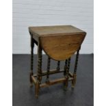 An oak drop leaf table with oval top on barley twist supports, 76 x 60cm