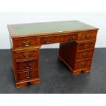 A yewwood desk, the rectangular top with green leather skivver with one central frieze drawer