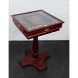 A glass topped Monopoly games board on a table support,complete with accessories to the drawers,