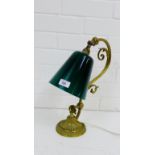 A brass desk lamp with green glass shade