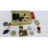 A box containing a quantity of late 19th and early 20th century medallions, pin badges and cap