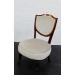 A mahogany framed nursing chair with upholstered shield back and seat, on turned legs and brass caps