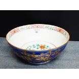 A blue glazed bowl, the exterior gilt painted with prunus trees with floral sprays to the interior