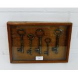A glazed showcase containing a collection of five iron keys, 30 x 21cm