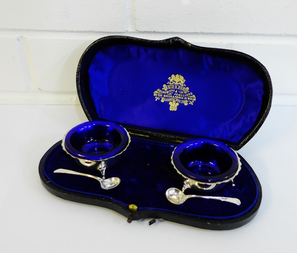 Edwardian pair of circular silver salts with blue glass liners, Chester 1901, in original fitted