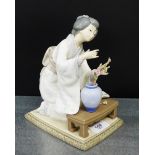 A Lladro porcelain figure of a Japanese lady, modelled kneeling, with a vase of flowers, 19cm high