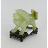 A pale green carved jadeite figure of a Temple Lion on hardwood stand, 7cm long