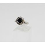 18 carat white gold and platinum sapphire and diamond cluster ring, the oval sapphire within a