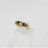 A diamond and sapphire five stone ring, claw set on a yellow metal band UK ring size M