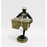 Painted novelty figure, modelled standing with a basket box in his arms, 13cm high