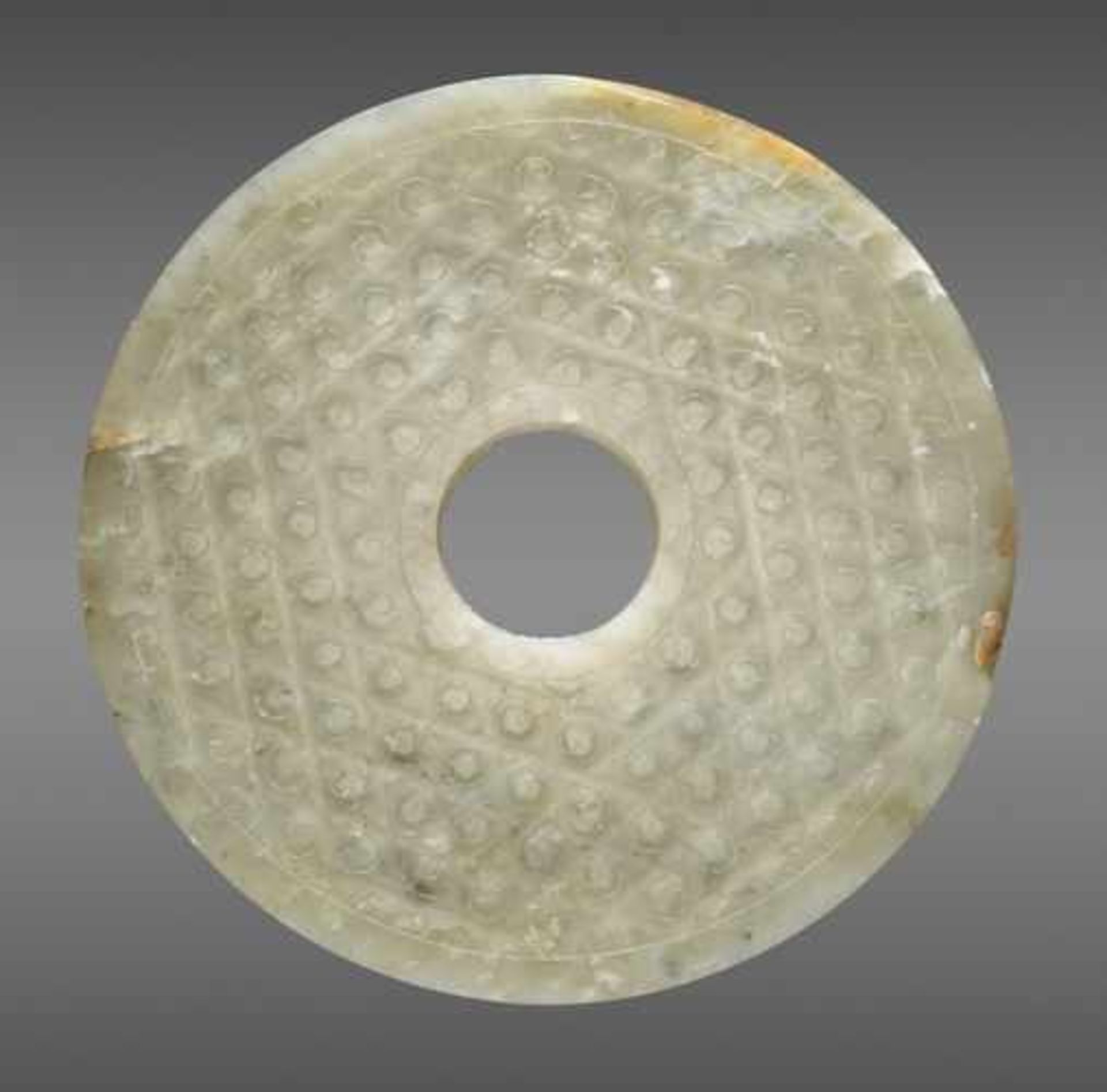 A TRANSLUCENT PALE GREEN DISC DECORATED WITH A PATTERN OF INCISED SPIRALS Jade, China. Western Han