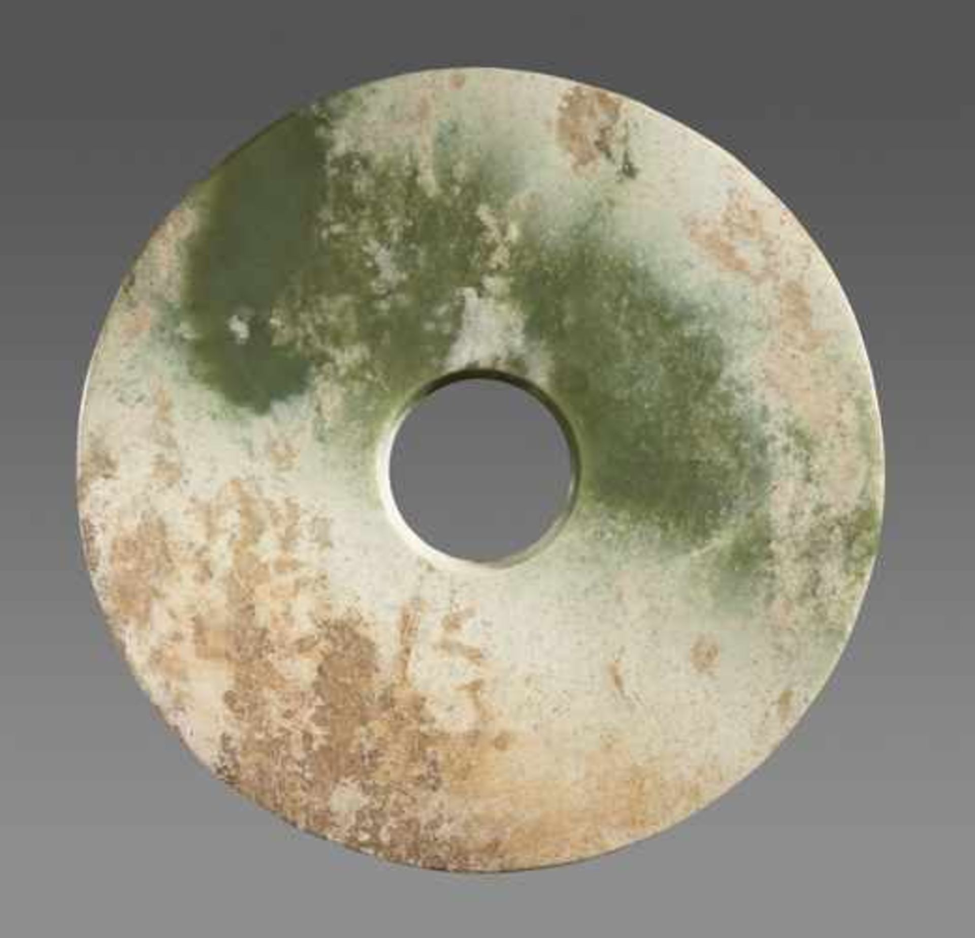 A LARGE SMOOTH BI DISC IN GREEN JADE WITH WHITENED AREAS Jade, China. Early Bronze Age, c. 2200-1600