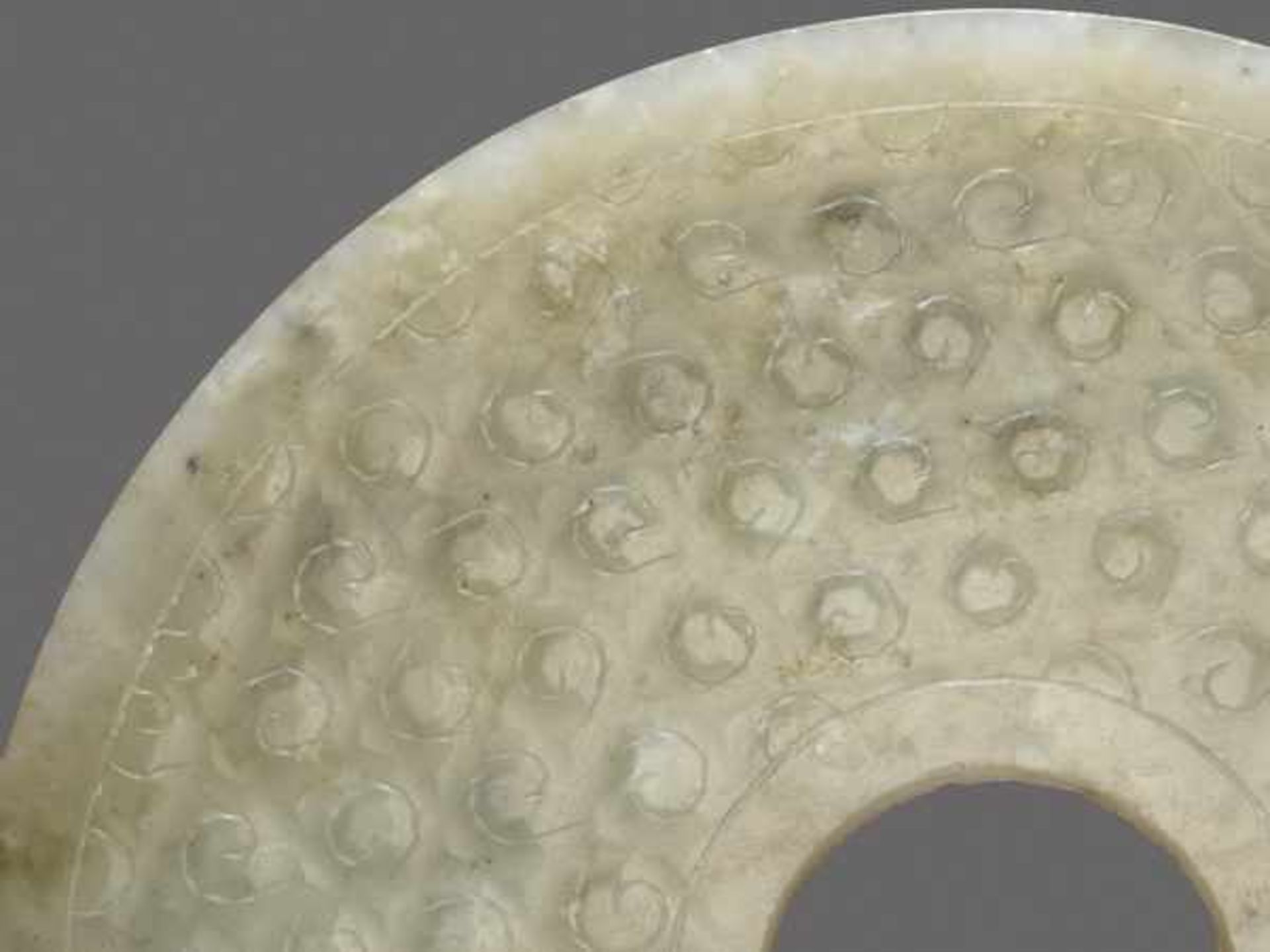 A TRANSLUCENT PALE GREEN DISC DECORATED WITH A PATTERN OF INCISED SPIRALS Jade, China. Western Han - Image 4 of 6