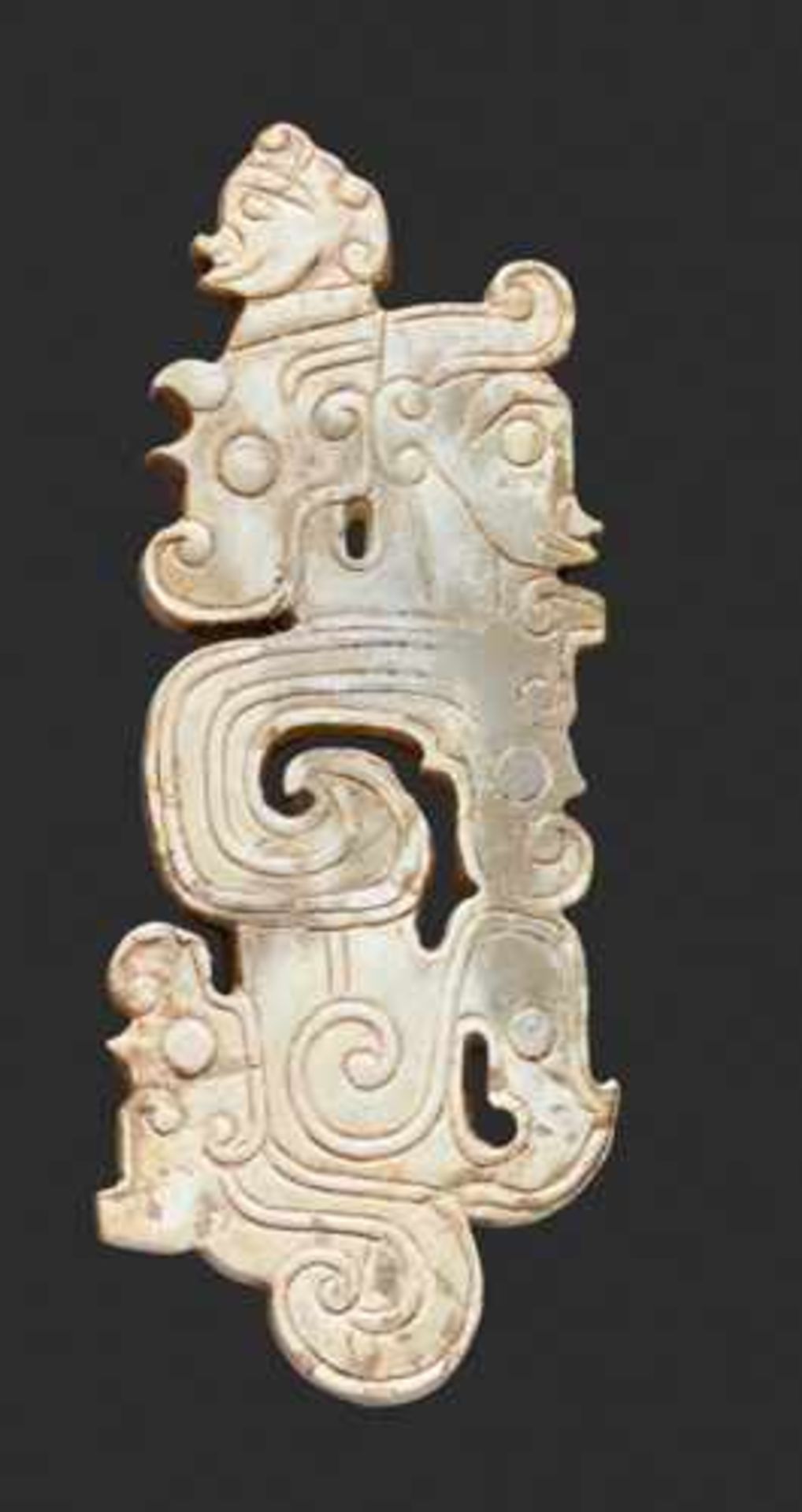 A SCULPTURAL ORNAMENT WITH A COMPOSITE MOTIF OF HUMAN HEADS AND DRAGONS Jade, China. Western Zhou,