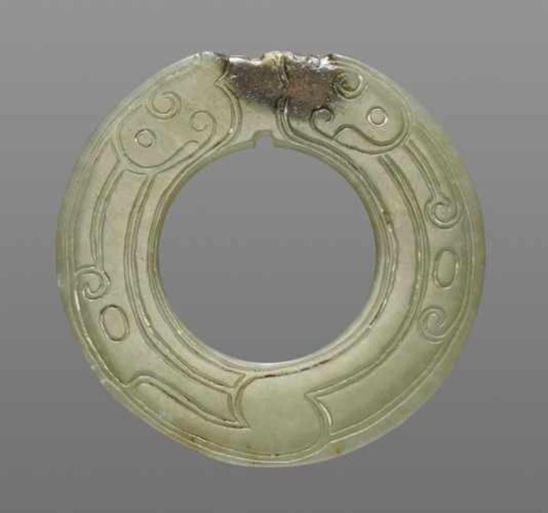 THIN AND DELICATE GREEN JADE RING WITH AN INCISED PATTERN OF STYLIZED DRAGONS Jade, China. Late