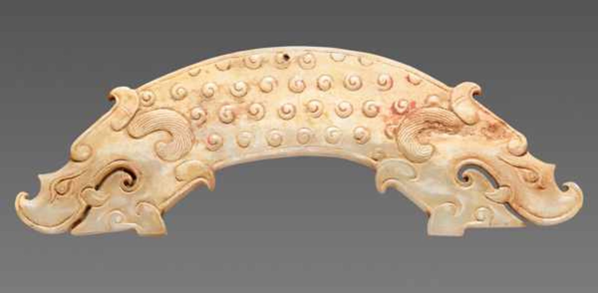 A POWERFUL HUANG ARCHED PENDANT WITH FINELY DETAILED DRAGON HEADS AND A PATTERN OF RAISED CURLS